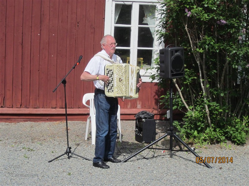 Musiker med dragspel framför Tossögårdens röda vägg