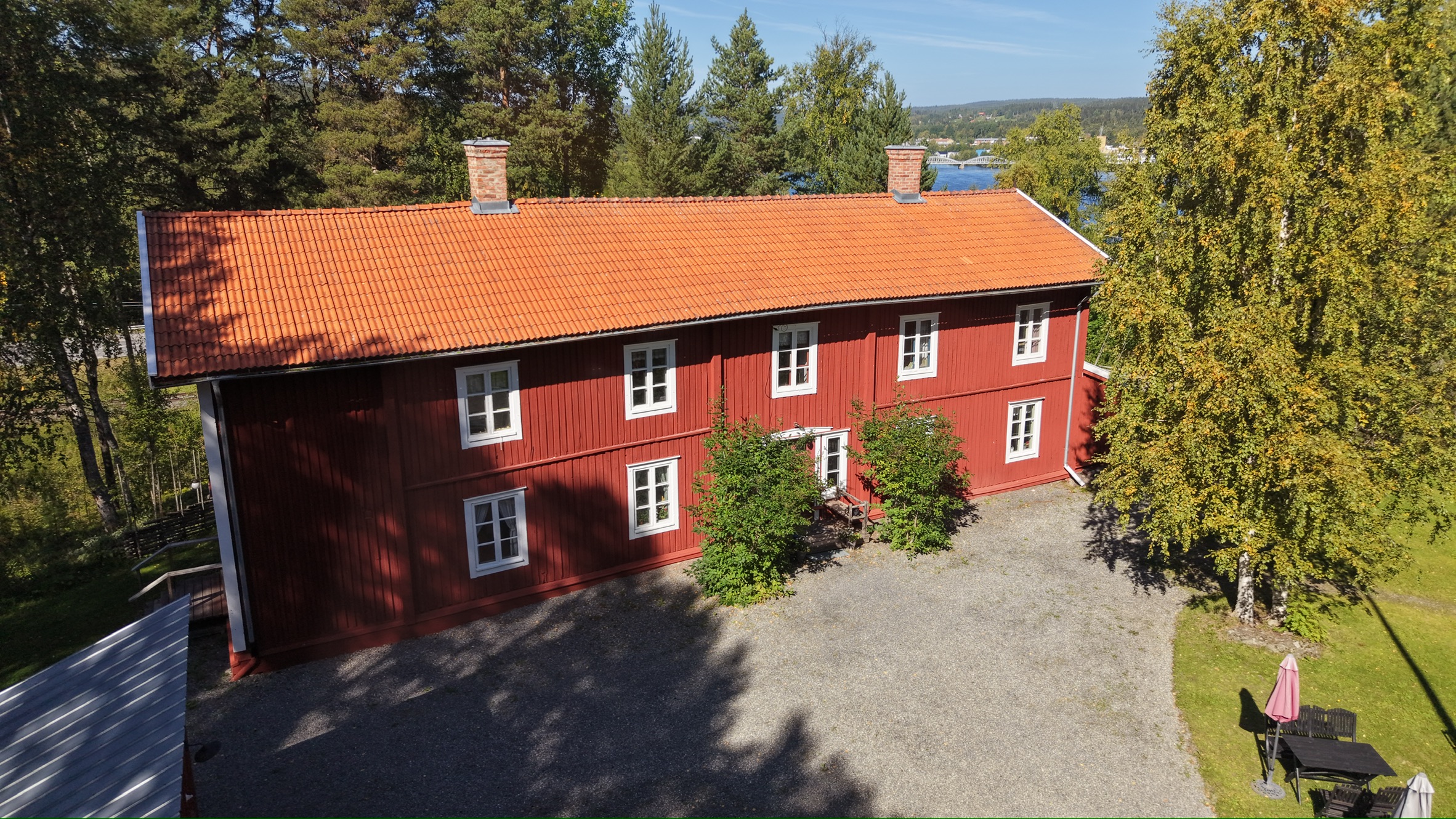 Tossögårdens faluröda huvudbyggnad sedd från luften med Indalsälven i bakgrunden